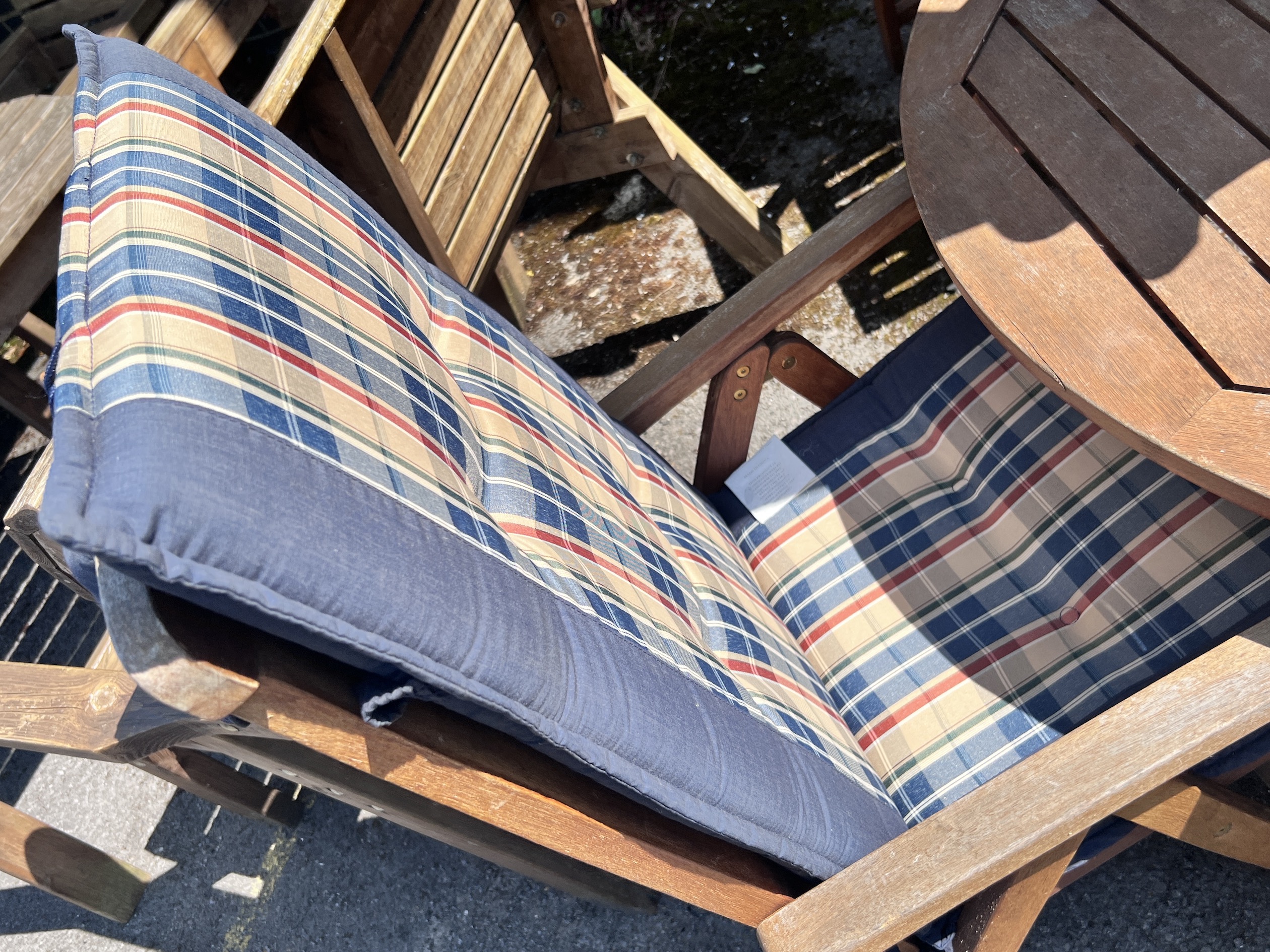 A Royal Craft teak folding table and four chairs with two cushions, parasol and cast metal base, table 110cm diameter, height 74cm.